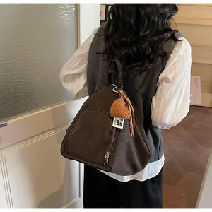Detailansicht eines dunkelbraunen Vintage-Rucksacks mit Herzanhänger am Modell