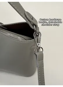 Détail du crochet en métal argenté et de la bandoulière amovible d'un sac en cuir gris