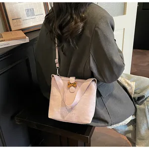 Detail of light purple suede bucket bag with embroidered logo and leopard bow accent