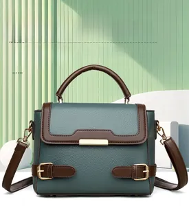 Detailed view of the dark green pebbled leather handbag with brown straps and gold lock