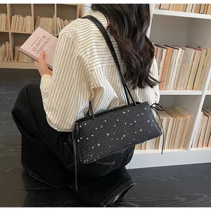 Sac sous le bras noir à motif d'étoiles porté par un mannequin dans un bureau chaleureux
