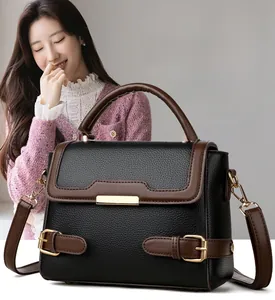 Detail of two-tone pebbled leather handbag with gold metal hardware and brown strap