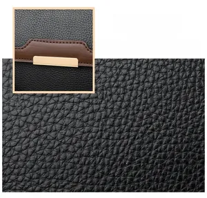 Detail of black lychee grain leather with brown trim and gold rectangular buckle