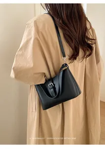 Détail d'un sac à bandoulière noir minimaliste avec boucle argentée porté par un mannequin