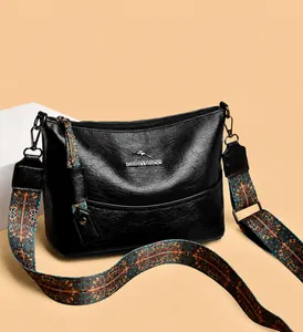 Detailopname van een leren tas met een brede schouderband met kleurrijke geometrische patronen