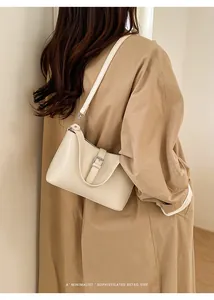 Gros plan du sac hobo minimaliste crème avec bandoulière réglable et boucle sur un modèle