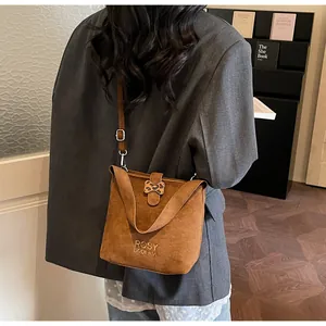 Rear view of model wearing a brown suede bucket bag with leopard print accent and logo