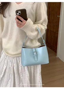 Détail du sac sous le bras en cuir bleu clair avec boucle argentée porté par un mannequin