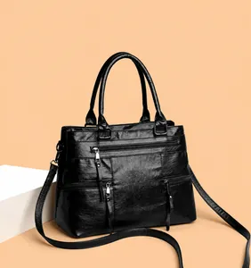 Detail view of black faux leather tote with multi-zipper pockets and dual handles