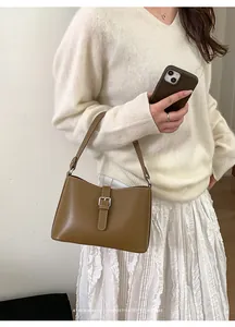 Détail du sac rétro en cuir marron avec boucle argentée et surpiqûres beige
