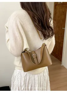 Sac à bandoulière chic en cuir marron avec boucle argentée porté par un mannequin