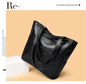 Close-up of black textured leather tote bag with side pocket on a minimalist pedestal