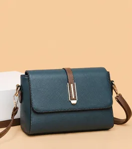 Detail of square shoulder bag showing blue pebbled leather and brown strap on yellow base