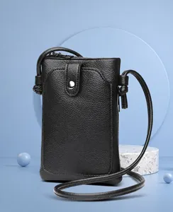 Détail macro du sac à téléphone noir en cuir grainé avec bouton pression et fermeture