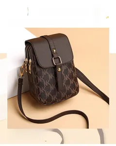Detailed close-up of a mini brown leather crossbody phone bag with monogram print