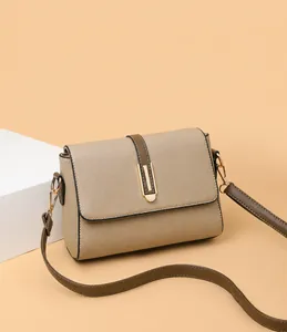 Close-up of beige faux leather crossbody bag with lychee texture and gold buckle detail