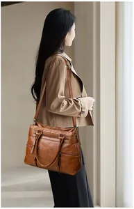 Macro shot of brown leather tote bag showing textured surface and multiple zipper pockets