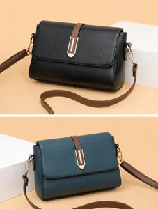 Detail of square leather shoulder bags in black and teal with gold buckles and litchi texture