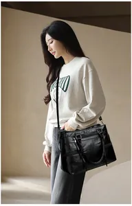 Detail of black leather tote bag showing smooth texture and functional zipper pockets