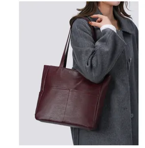 Detail of burgundy soft leather tote bag showing fine stitching and spacious front pocket