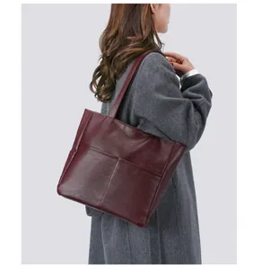 Detail of burgundy textured leather tote bag with front pocket showing large capacity
