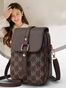 Detail of dark brown leather phone bag with NK monogram pattern and gold metal hardware