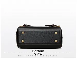 Detail view of black lychee grain leather handbag bottom with gold protective studs