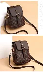 Close-up of brown cross-body phone bag featuring NK monogram and dual zipper detail