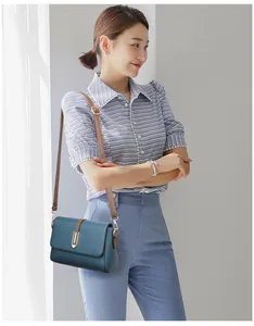 Detail of blue pebbled leather crossbody bag with gold metal buckle and brown strap