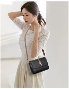 Detail of black lychee grain crossbody bag with brown strap and gold metal buckle