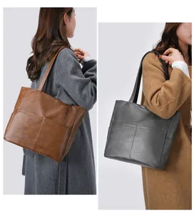Detail of soft leather tote bag with lychee texture and cross stitching in brown and gray