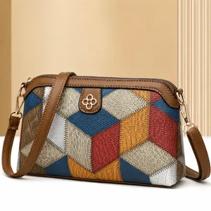 Close-up of geometric patchwork crossbody bag with textured leather and gold floral metal tag