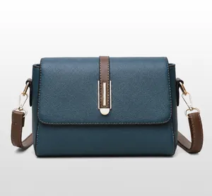 Detail of blue textured leather shoulder bag featuring a brown strap and golden buckle