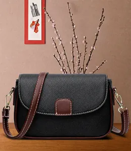 Detail van zwarte leren crossbodytas met bruine rand en contrasterende stiksels
