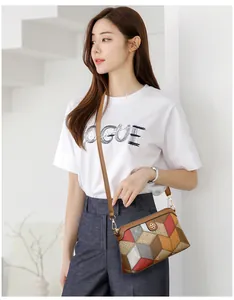 Dettaglio della borsa a tracolla bohemian con patchwork geometrico e logo in metallo