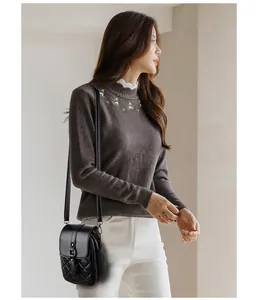 Detailed view of a black quilted crossbody phone bag worn by a model in casual attire