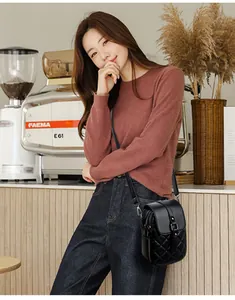 Quilted black crossbody phone bag with chain strap shown on a model in a cafe setting