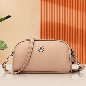 Dettaglio borsa a tracolla beige con pelle martellata e logo a quadrifoglio argento
