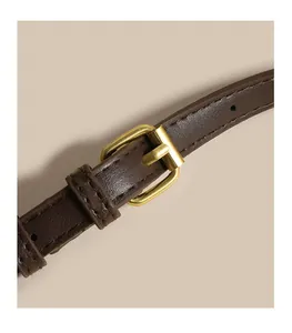 Close-up of brown leather bag strap with textured finish and golden metal buckle