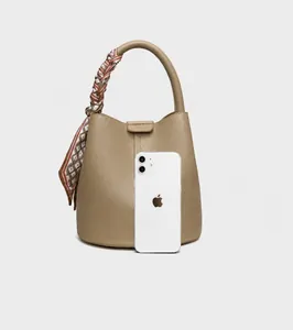 Size comparison between khaki bucket bag and iPhone 12 showing compact capacity