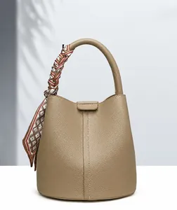 Detail of khaki bucket bag featuring lychee texture and silk scarf wrapped on handle