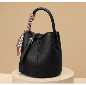 Detailed view of black litchi grain leather bucket bag with silk scarf on handle
