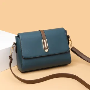 Blue leather crossbody bag with brown straps and golden buckle shown at 45-degree angle
