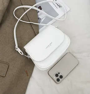 Λευκή μίνιμαλ τσάντα χιαστί δίπλα σε ένα iPhone 12 για σύγκριση μεγέθους προϊόντος