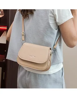 Μπεζ τσάντα σέλας με ανάγλυφο 'Fashion Trends' φορεμένη από μοντέλο σε στυλ καθημερινής ζωής