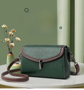 Detail of dark green leather handbag featuring contrast white stitching and metal buckle lock