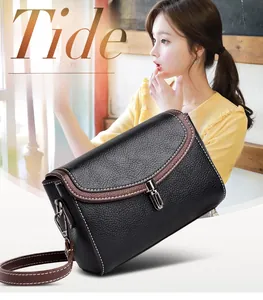 Detail view of black lychee leather crossbody bag with brown trim and silver buckle