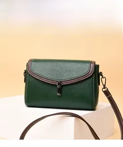 Detail of dark green lychee grain leather handbag with contrast stitching and metal buckle