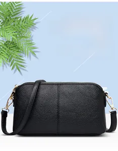 Detail of black cross-body bag featuring lychee pattern leather and gold metal zipper