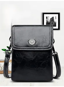 Detail of black leather phone bag showing contrast stitching and sun-shaped metal buckle